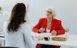 Teilpension 2026 | Ältere Frau bespricht etwas mit jüngerer Frau an Bürotisch