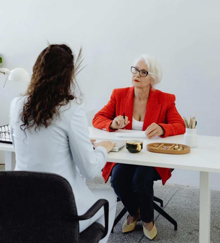 Teilpension 2026 | Ältere Frau bespricht etwas mit jüngerer Frau an Bürotisch