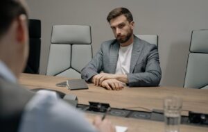 Mitarbeiter:innen richtig als Verantwortliche Beauftrage bestellen: Mann sitzt an einem Besprechungstisch