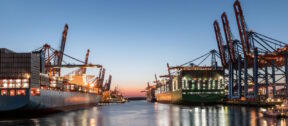 Thrive Index - Werft mit beleuchteten Containerschiffen am Abend