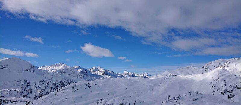 Verschneite Berglandschaft von Obertauern mit blauem Himmel, Gipfel in der Sonne und einigen Wolken