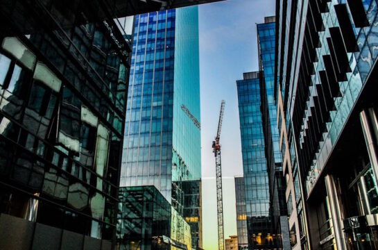 Steuergestaltung - Kran inmitten von Firmengebäuden mit Glasfronten